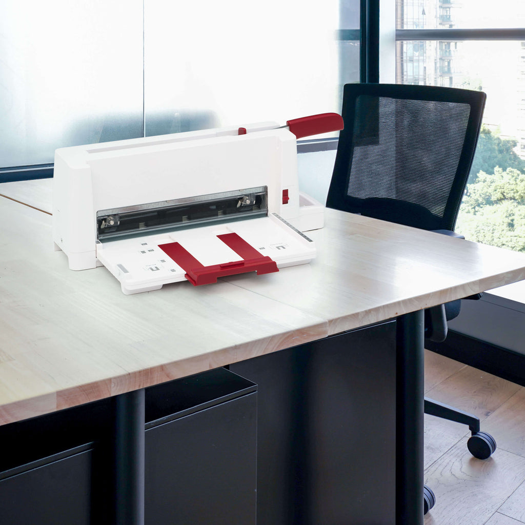 Der transportable Office-Bürostapelschneider IDEAL 3006 steht in einem modernen Büro mit Holzboden auf einem Holz-Schreibtisch, im Hintergrund ein Fenster mit Blick ins Grüne, neben dem Schreibtisch steht ein schwarzer Schreibtisch-Stuhl auf Rollen.