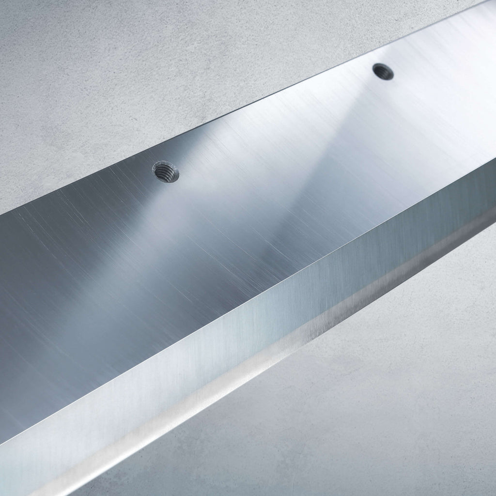 Vor einem weichen, grauen Hintergrund eine Nahaufnahme eines hochwertigen IDEAL-Stapelschneider-Messers aus Qualitätsstahl mit glatter, gebürsteter Metalloberfläche.