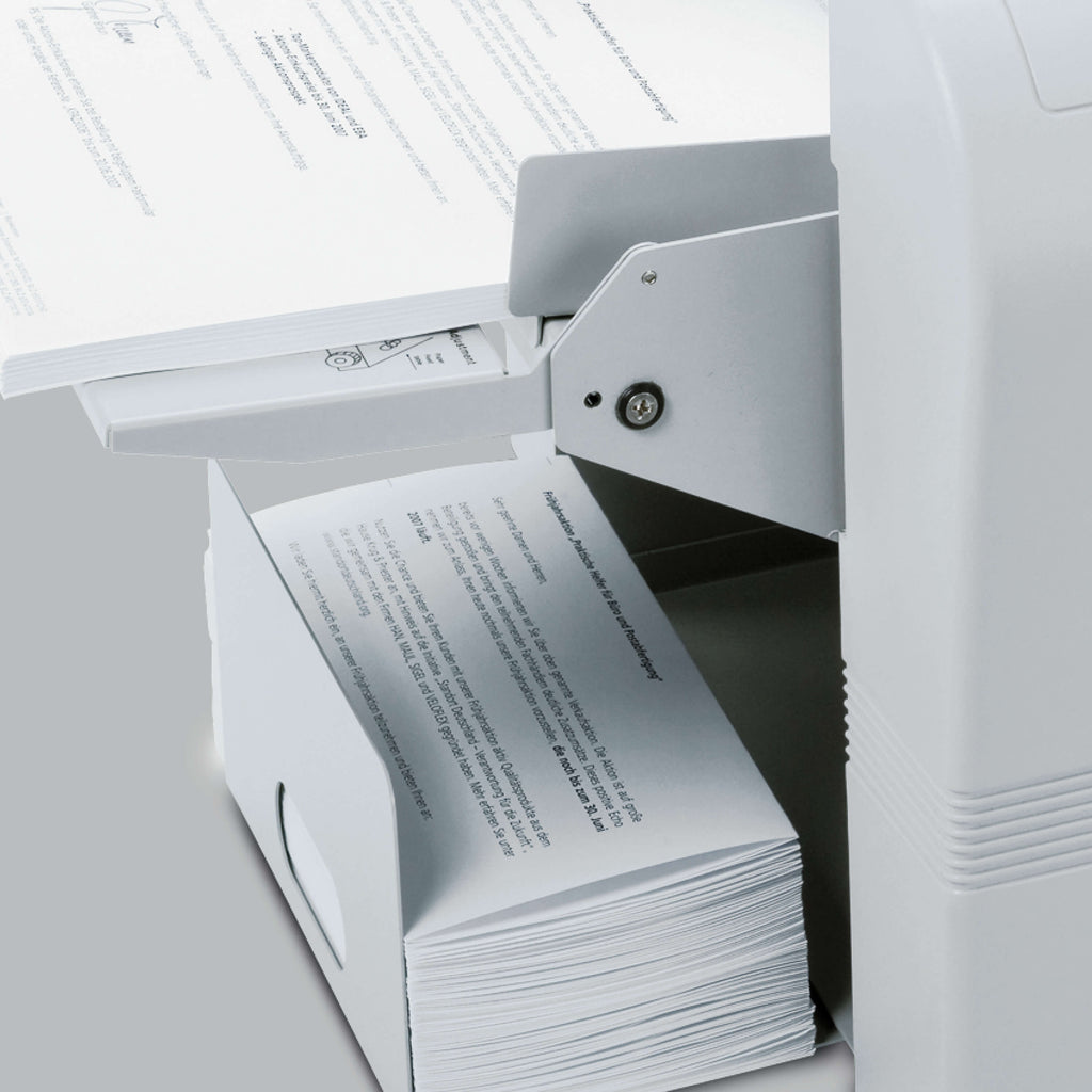 Im Papierauswurf-Fach der elektrischen Büro-Falzmaschine IDEAL 8324 befinden sich korrekt auf DIN lang gefalzte Briefe. Oberhalb auf dem Papier-Zuführtisch der Maschine liegen noch zu falzende Briefe im A4-Format.