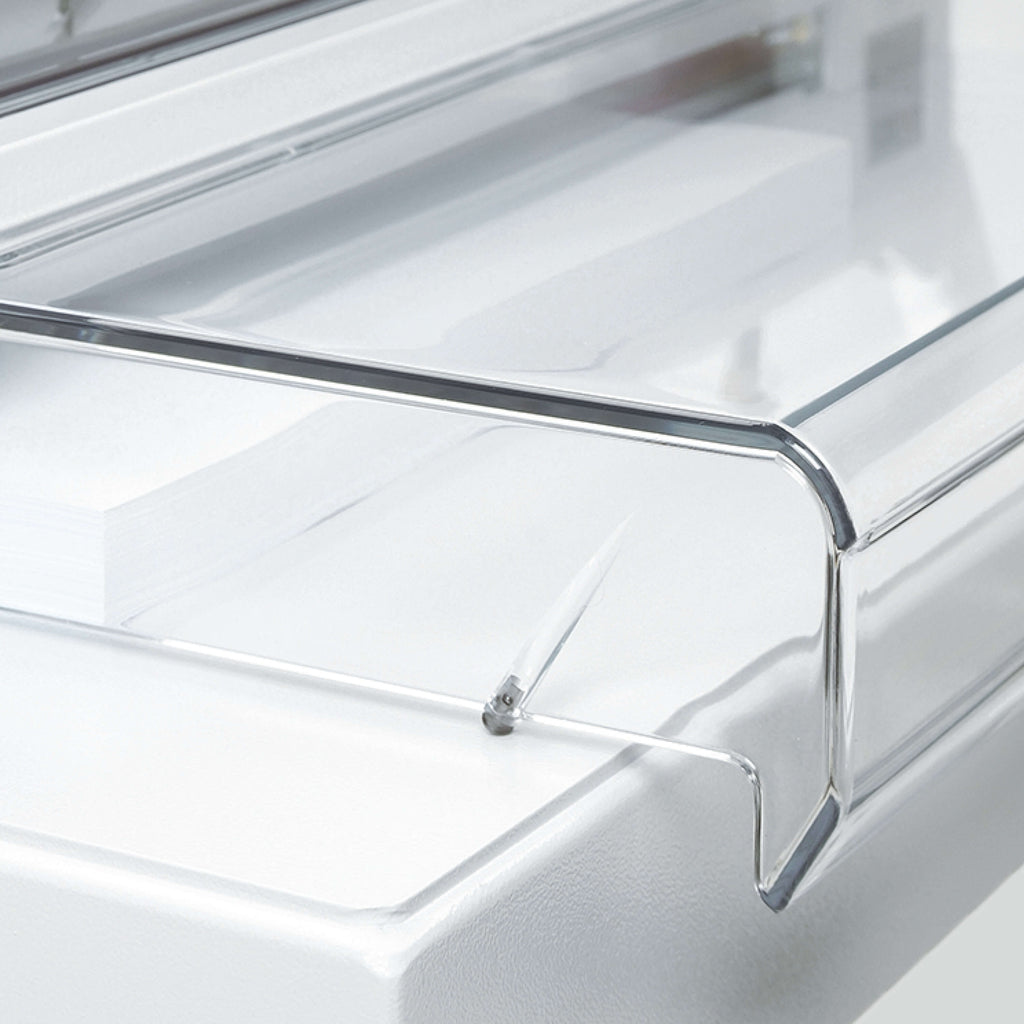 Detailansicht eines elektrischen IDEAL Papier-Stapelschneiders. Zu sehen die transparente Sicherheits-Haube. Der Blick fällt auf einen Teil des metallenen Maschinentischs.