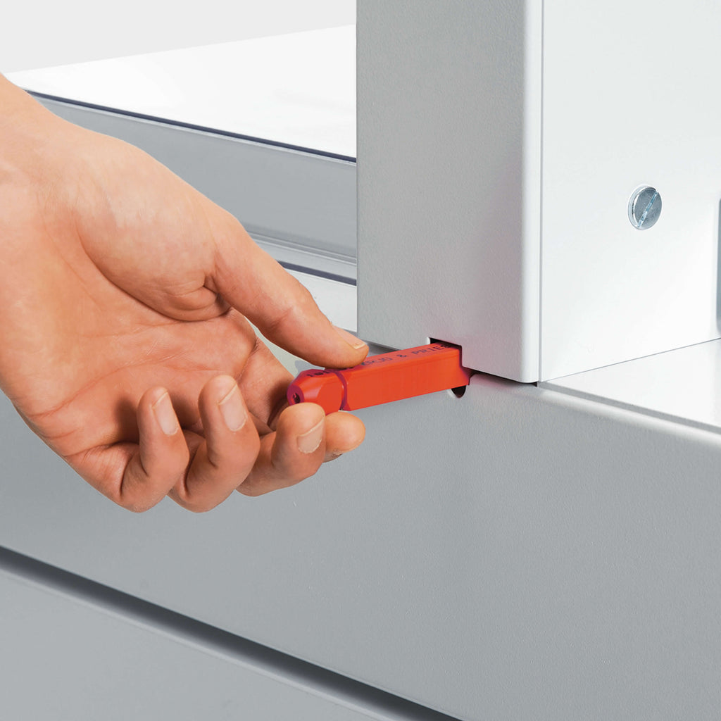 Das Bild zeigt in Nahaufnahme den Schnittleisten-Wechsel bei einem IDEAL-Stapelschneider. In der Szene hält eine Hand die rote Schnittleiste beim Austausch.