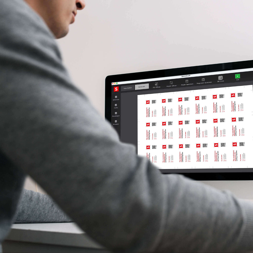 Ein von hinten fotografierter Bediener des programmierbaren Stapelschneiders IDEAL THE56 oder IDEAL THE68 blickt auf den Monitor eines Laptops, auf dem ein Schnittbogen mit einer Reihe von Nutzen angezeigt wird. Das Bild symbolisiert die Impositioning-Option der Schnittautomatisierungs-Software Speedcut.