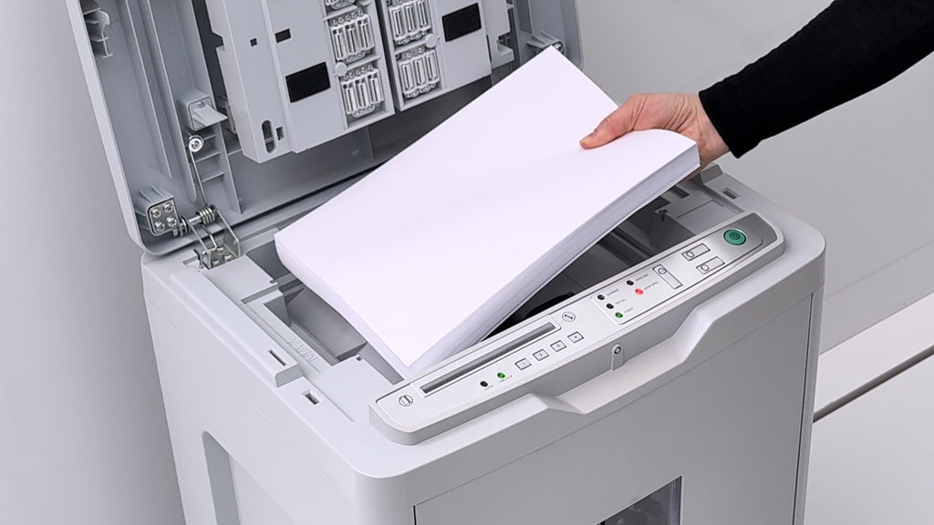 Top view of the Shredcat 8285 Autofeed document shredder for the automatic destruction of entire stacks of paper. The flap is open and a hand is inserting the stack of paper.