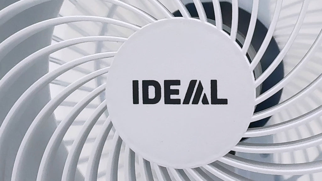 Nahaufnahme des Gehäuses des Ventilatorkopfs des IDEAL FAN1 – hinter einem Schutzgitter sind die Rotationsflügel sichtbar. Auf dem weißen Gehäuse ist das aufgedruckte IDEAL-Logo zu sehen.