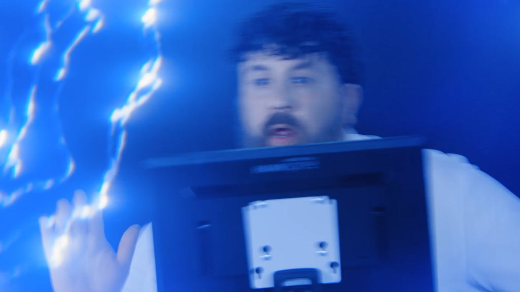 Vorschaubild zu einem futuristischen Werbevideo im Stil von Zurück in die Zukunft: Im Mittelpunkt steht ein bärtiger Typ, der mit sichtlicher Begeisterung den programmierbaren Stapelschneider IDEAL THE 56 bedient. Er steht hinter dem großen 15,6“-Bedienmonitor, lacht, tanzt auf der Stelle und feiert die Technik. Im Hintergrund zucken Blitze, die Szenerie ist in leuchtendem Blau und Schwarz gehalten – eine augenzwinkernde Hommage an Doc Brown und die Power von 1.21 Gigawatt.